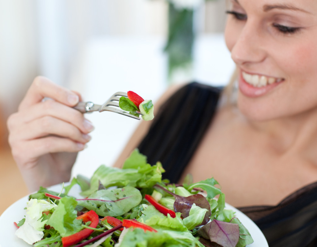 Close-up of a smiling woman eating a salad
