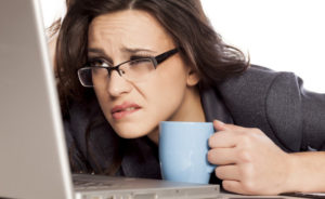 Sleepy and tired business woman on laptop, holding a coffee