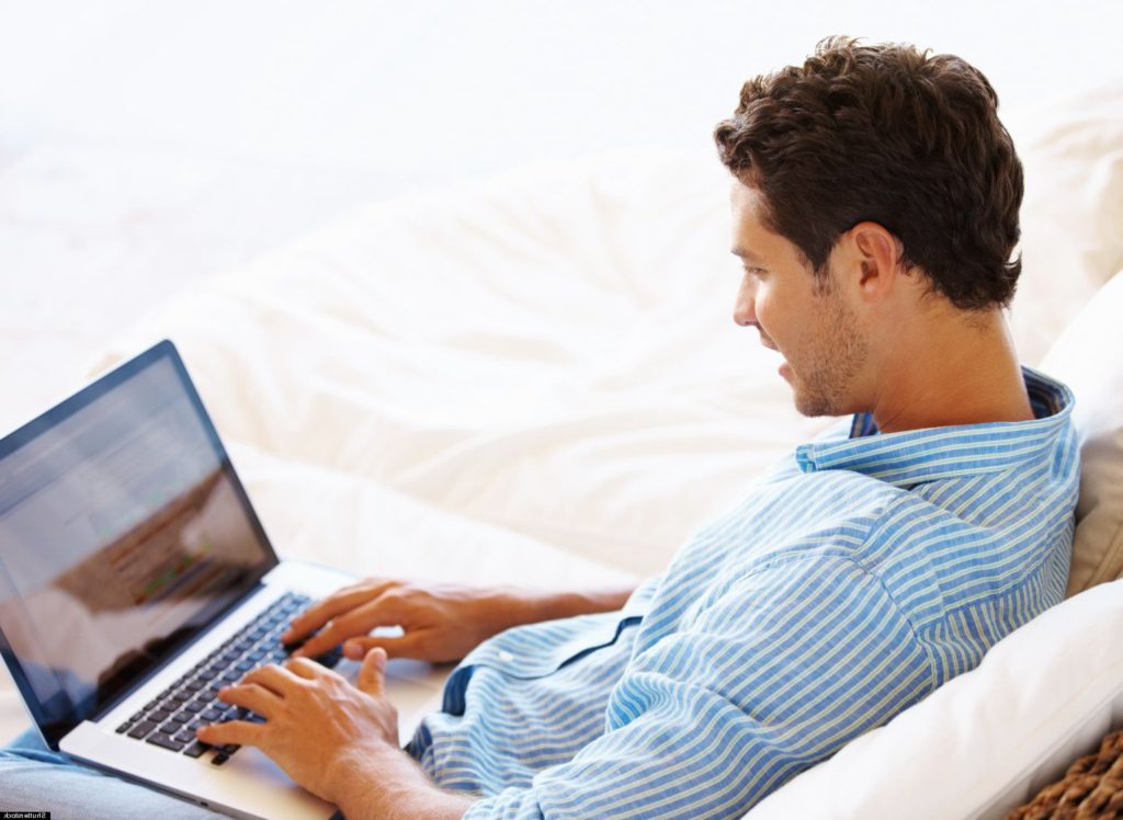 Hombre-sentado-mirando-a-su-laptop-y-escribiendo-en-el