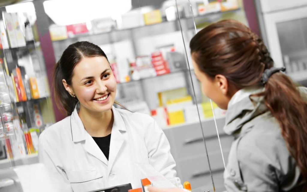 Una-dependienta-de-un-negocio-hablando-con-una-cliente-a-traves-de-un-cristal-en-un-comercio