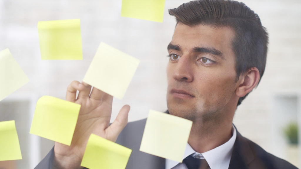 Handsome businessman reading carefully information on adhesive notes